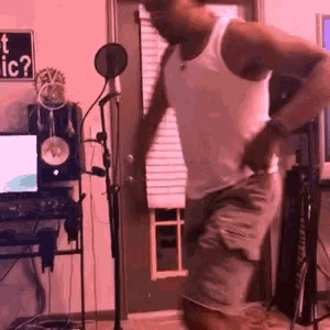 a man in a white tank top and shorts is standing in front of a microphone .