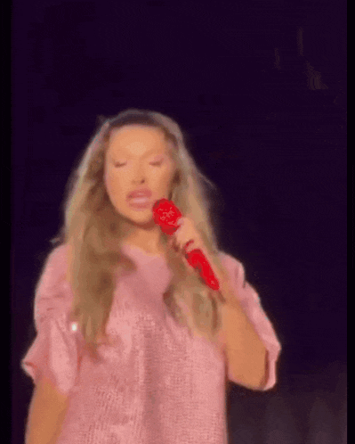 a woman in a pink shirt is holding a red microphone and saying yes b1tch .