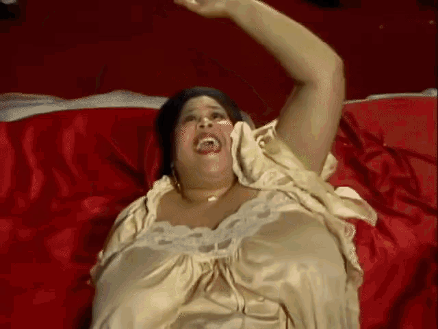 a woman laying on a bed with her arms outstretched and her mouth open