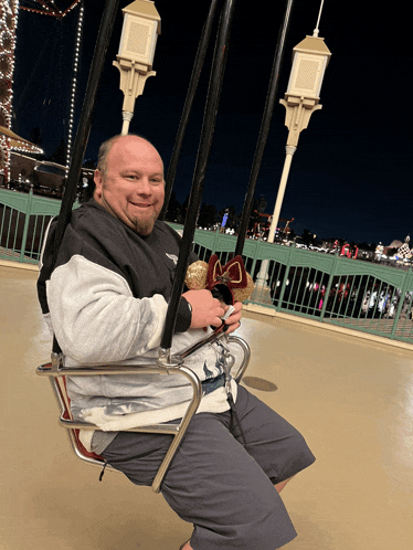 a man sitting on a swing holding a mickey mouse headband