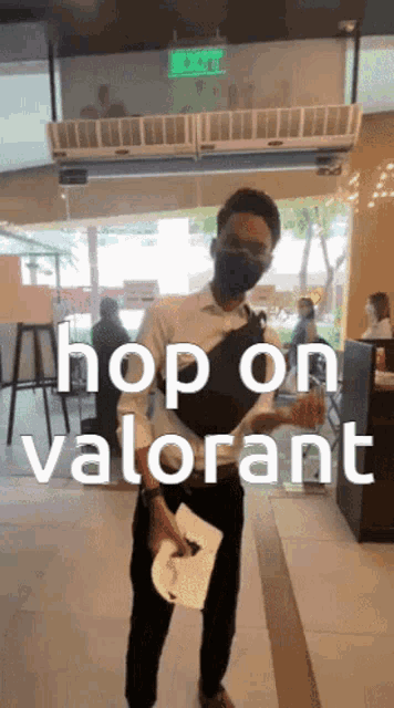a man wearing a mask stands in front of a sign that says " hop on valorant "
