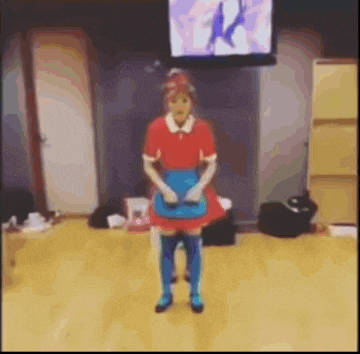 a woman in a maid costume is standing on a wooden floor in front of a television .