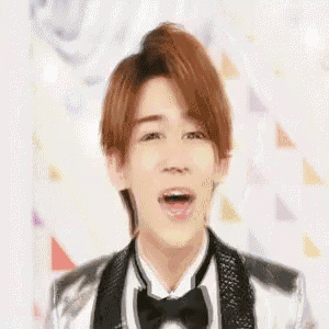 a young man wearing a tuxedo and bow tie is singing .