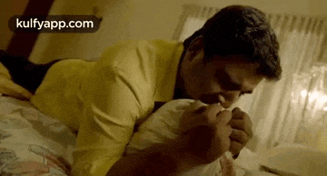 a man is laying on a bed kissing a woman 's hand .