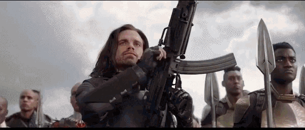 a man is holding a gun in front of a group of soldiers .