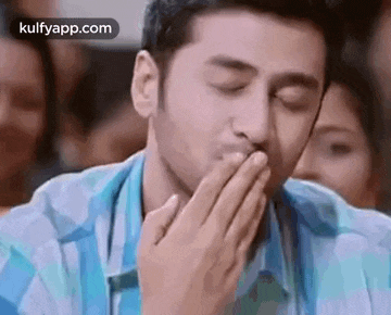 a man is covering his mouth with his hand while yawning .