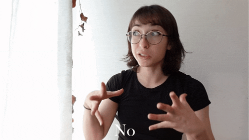 a woman wearing glasses and a black shirt says no with her hands