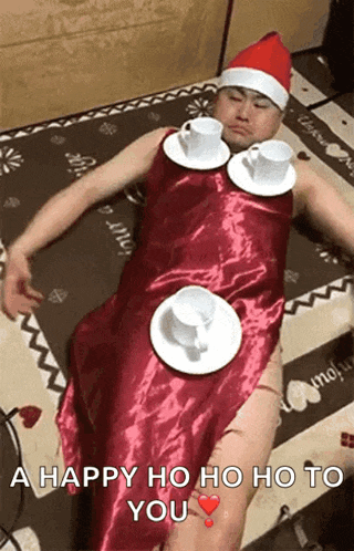a man is laying on a bed wearing a santa hat and a red dress