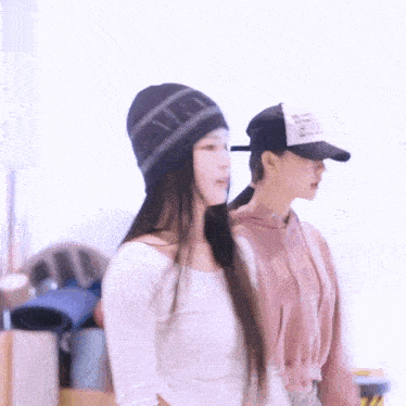 two women are standing next to each other wearing hats and sweaters .