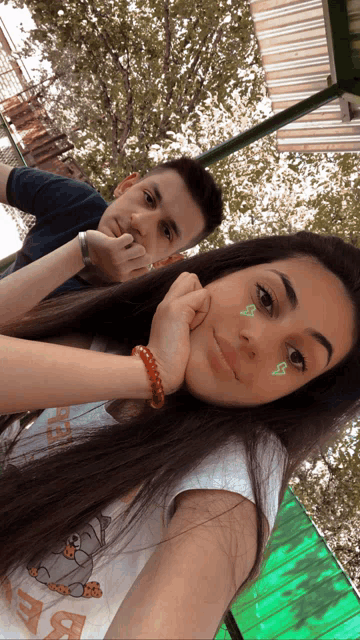 a boy and a girl are posing for a picture and the girl has a sticker on her face that says ' s '