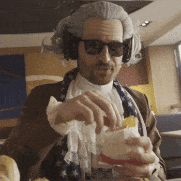a man wearing a wig and sunglasses is eating a mcdonalds hamburger