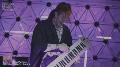 a man in a kimono is playing a keyboard in front of a purple background that says youtube music week