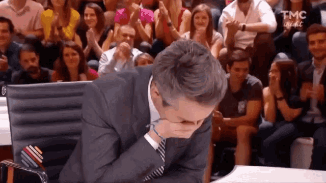 a man in a suit and tie is sitting in a chair with his hand on his face .