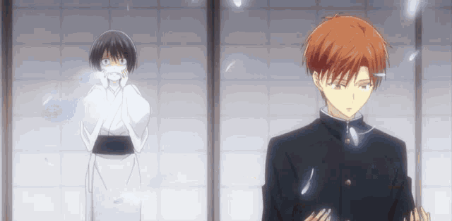 a boy and a girl are standing next to each other in front of a window .