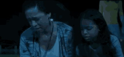 a woman and a young girl are sitting next to each other in the dark .