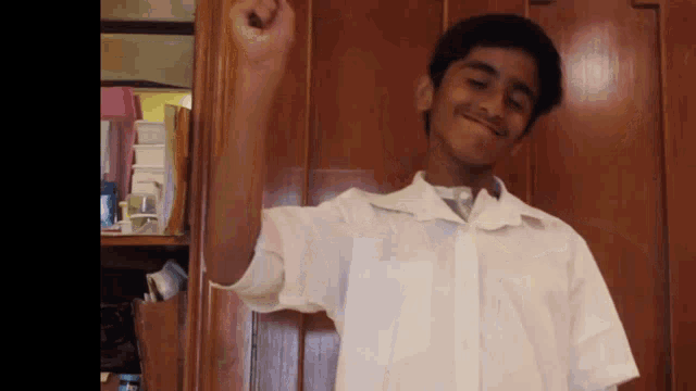 a young boy in a white shirt is standing in front of a wooden wall