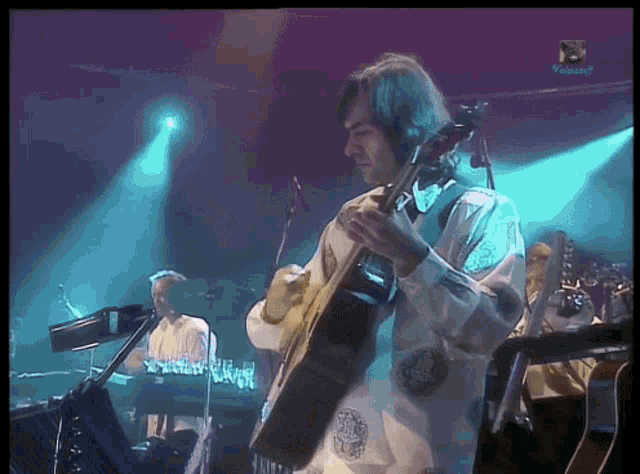 a man playing a guitar on a stage with a watermark that says ' visual ' on the bottom right