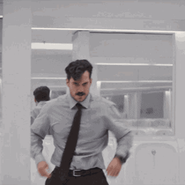 a man with a mustache wearing a grey shirt and tie