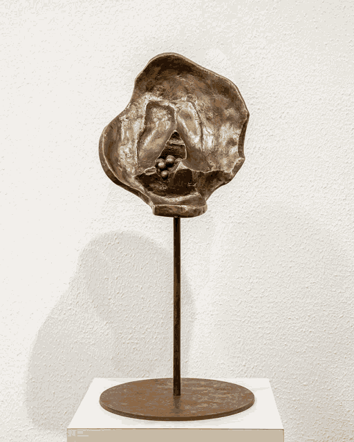 a sculpture on a pedestal with a white wall in the background