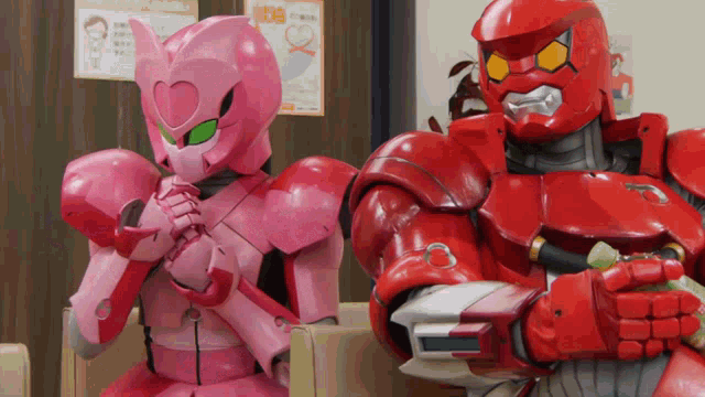 a pink robot and a red robot are sitting on a couch