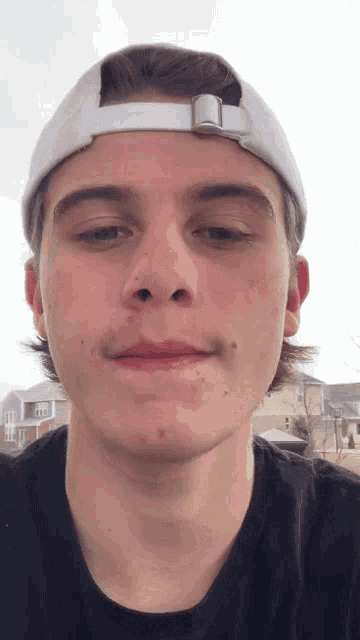 a young man wearing a white baseball cap and a black shirt