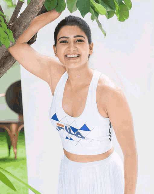 a woman wearing a white fila crop top is smiling