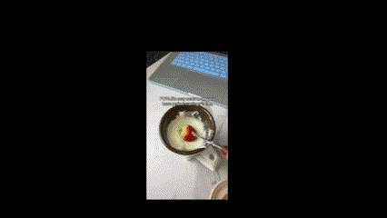 a bowl of food with a spoon in it and a laptop on a table .