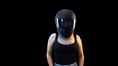 a woman wearing a black motorcycle helmet is standing with her arms crossed against a black background .
