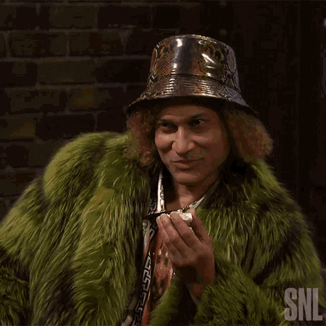 a man wearing a green fur coat and a hat with snl on the bottom right