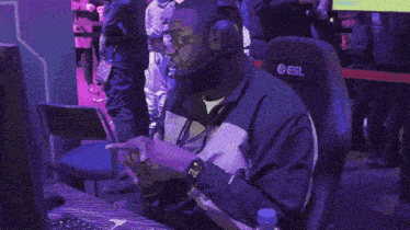 a man wearing headphones sits in front of a computer with a bottle of aquafina water next to him