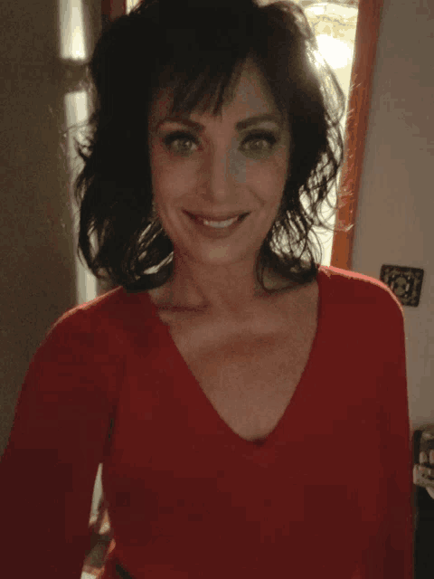a woman wearing a red sweater is smiling for the camera