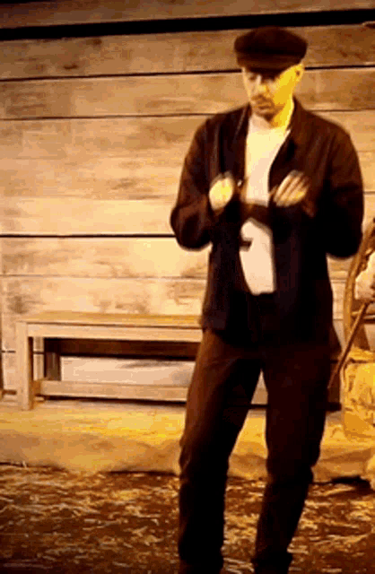 a man wearing a hat is standing in front of a wooden bench
