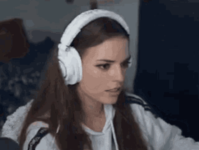 a woman is wearing headphones and looking at the camera .