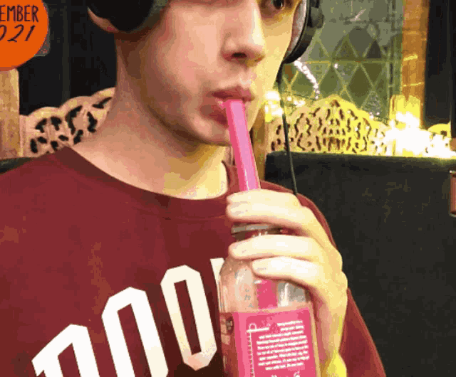 a man drinking through a pink straw wearing a shirt that says 100
