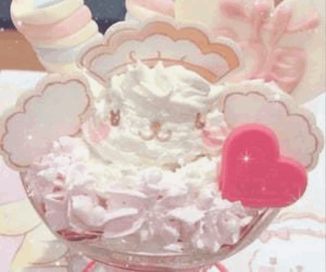 a close up of a dessert with whipped cream and a heart in a glass bowl .