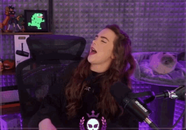 a woman singing into a shure microphone while sitting in a chair .