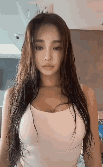 a woman with long dark hair is wearing a white tank top