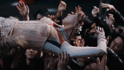 a woman in a corset is being held up by a crowd of people with their hands in the air