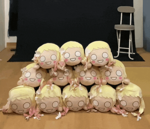 a bunch of stuffed dolls are stacked on top of each other on a wooden floor