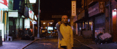 a man stands on a street with a sign that says tbh on it