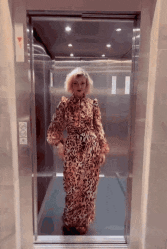 a woman in a leopard print dress is walking into an elevator