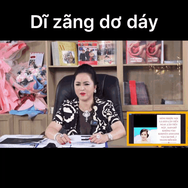a woman sits at a desk in front of a sign that says di zăng do day