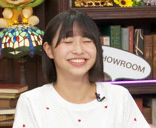 a young woman is smiling in front of a bookshelf with a lamp and a sign that says howroom .
