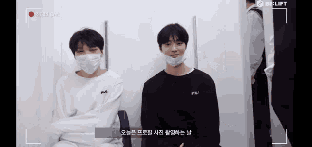 two young men wearing face masks are sitting in front of a camera that says be-lift on it