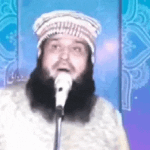 a man with a beard is singing into a microphone in front of a blue background .