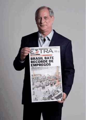 a man in a suit is holding up a newspaper that says extra brasil bate recorde de empregos