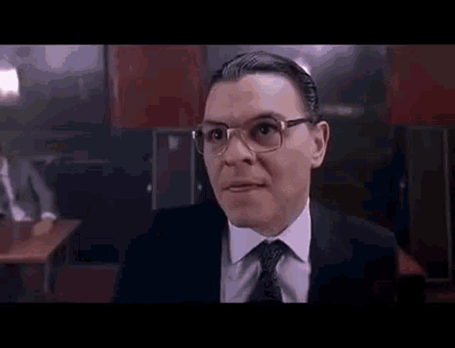 a man with glasses is clapping his hands in a restaurant .