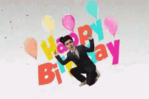 a man in a suit and tie is jumping in the air with balloons and the words happy birthday behind him