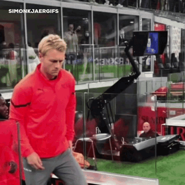 a man in a red puma shirt stands on a field