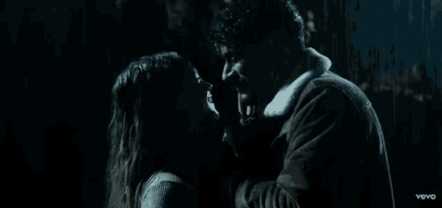 a man and woman are kissing in the rain .